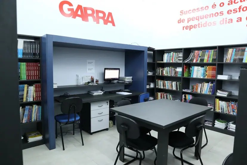 Biblioteca do Garra com estantes de livros e mesa de estudos