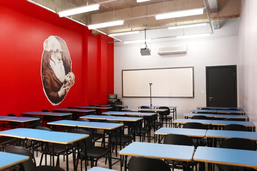 Sala de aula climatizada do Garra com carteiras azuis e parede vermelha